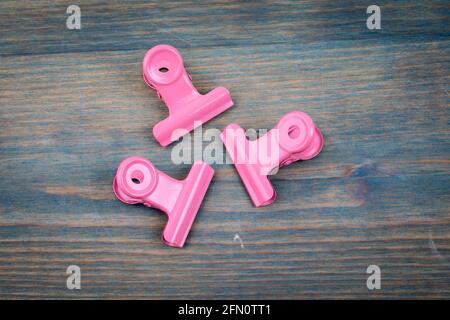 Pink metal paper clip on a painted wooden green texture background. Stock Photo