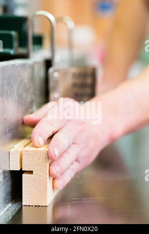 Carpenter working on an electric buzz saw or wood milling and cutting some boards in carpentry Stock Photo