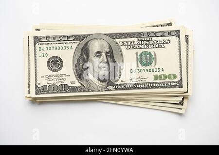 A money pile of stacked one hundred US banknotes with president Franklin portrait on white background. Cash of hundred dollar bills, paper money curre Stock Photo