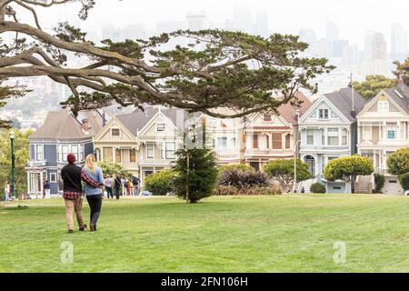 SAN FRANCISCO, CALIFORNIA - July 24, 2018: A couple of tourists enjoying the view of Painted Ladies, colorful Victorian houses in a row on a summer da Stock Photo