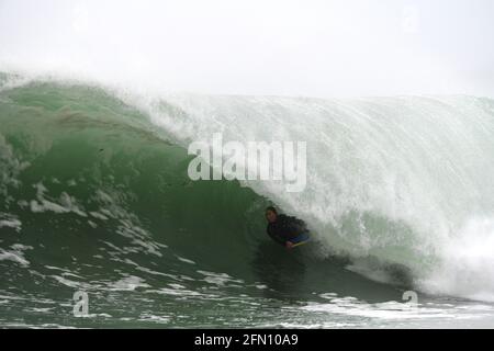 Surfing in Cornwall. A bodyboarder rides deep inside the tube of a large wave Stock Photo