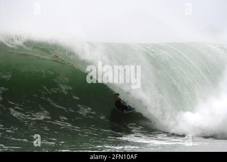 Surfing in Cornwall. A bodyboarder rides deep inside the tube of a large wave Stock Photo