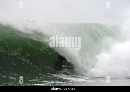 Surfing in Cornwall. A bodyboarder rides deep inside the tube of a large wave Stock Photo