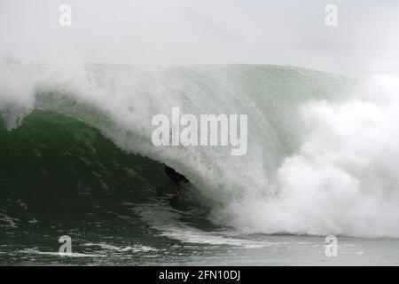 Surfing in Cornwall. A bodyboarder rides deep inside the tube of a large wave Stock Photo