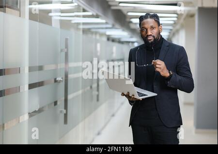 Smiling African American businessman standing alone in a large office Stock Photo