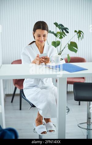 Spa client in a waffle weave bathrobe using her gadget Stock Photo