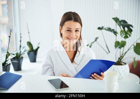 Joyous woman with a brochure in her hands looking ahead Stock Photo