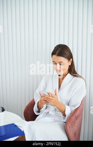 Pretty woman using her cellphone in a beauty salon cafe Stock Photo