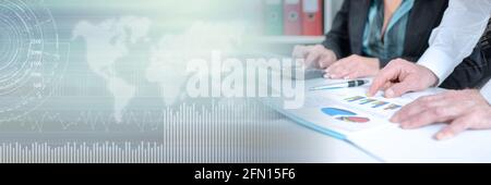 Workteam in office analyzing graphs and using a calculator; panoramic banner Stock Photo