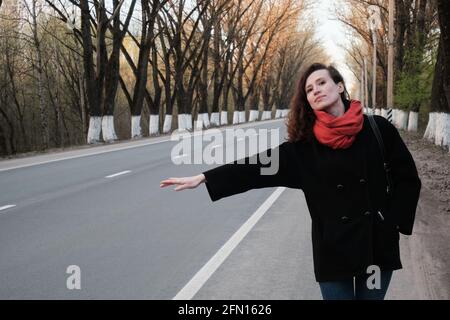 The girl tries to stop the car on the road Stock Photo