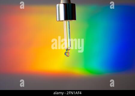 A Glass dropper on a prism rainbow background. Futuristic beauty Stock Photo
