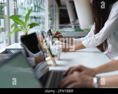 Side view of female office workers working together and typing on keyboard in modern office room Stock Photo