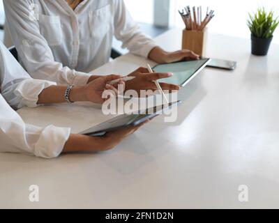 Cropped shot of female hands using digital tablets while sitting beside each other in library Stock Photo