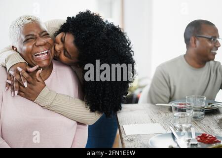 Happy african daughter having tender moment during lunch at home - Main focus on mother face Stock Photo