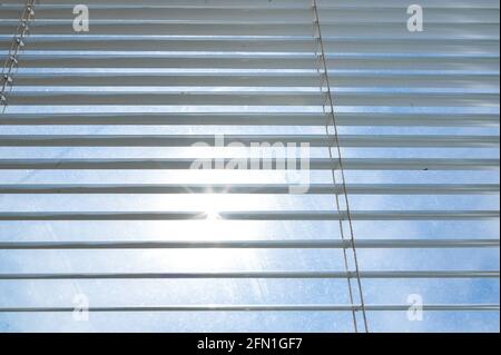 Sun shining through window blinds. The bright sun breaks through the ajar blinds. Stock Photo