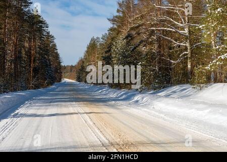 Car highway in the countryside through the forest on a winter sunny day Stock Photo