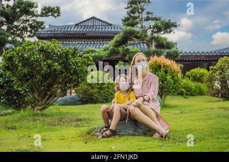 Mother and son travelers in medical mask looking at the Japanese traditional building. Tourists travel in Japan after the coronavirus epidemic Stock Photo