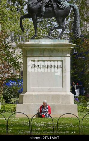 London, England, UK. Woman relaxing with a flask of tea by the statue of William II in St James's Square, SW1 Stock Photo