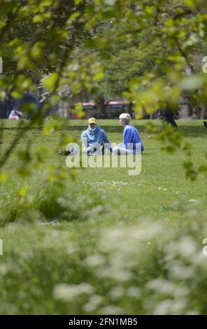 London, England, UK. Two people sitting on the grass in Green Park Stock Photo