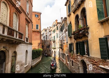 Venice. Two gondolas with gondoliers and tourists in a narrow canal of the Venetian lagoon, typical rowing boat. Sightseeing tour in the famous city. Stock Photo