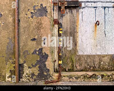 Old rusted padlock fixed to bolt on wooden door Stock Photo