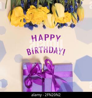 Square birthday greeting card happy birthday with yellow tulip flowers and purple gift boxes Stock Photo