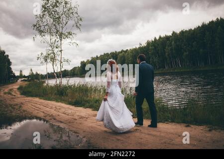 the newlyweds hold beautiful crystal glasses in their hands, the tradition of drinking alcohol at a wedding, a toast in a restaurant from the bride an Stock Photo