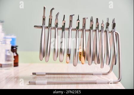 Set of different stainless steel instruments for braces. Silver removing pliers, cutters, removers, other orthodontic tools on wooden table in dental clinic. Concept of dentistry, dental instruments. Stock Photo