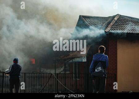 the fire destroys the building. the fire brigade pours water on the burning house. people are suffocating from the smoke and smog from the fire. fire Stock Photo