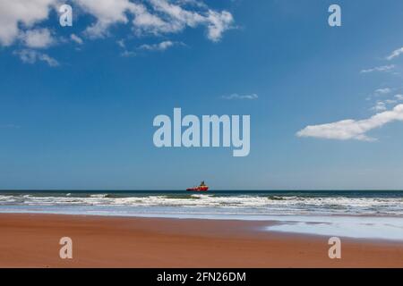 LUNAN BAY AND BEACH ANGUS SCOTLAND THE BLUE SEA WITH AN ANCHORED ORANGE OIL RIG SUPPORT VESSEL Stock Photo