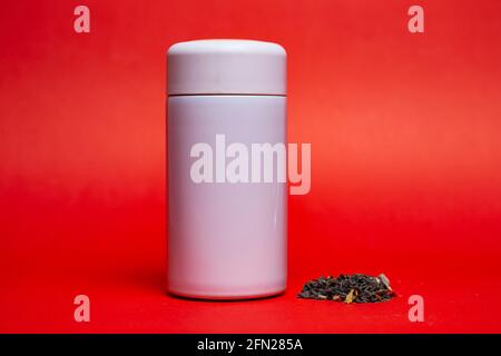 white thermos with green leaf tea on a red background. Stock Photo