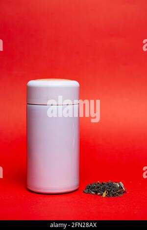 white thermos with green leaf tea on a red background. Stock Photo