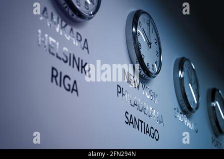 Many wall clocks on the white wall of business office showing time of different cities of the world Stock Photo