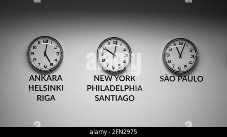 Many wall clocks on the white wall of business office showing time of different cities of the world Stock Photo