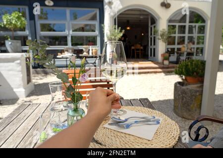 woman relaxing with a glass of white wine in a garden of restaurant Stock Photo