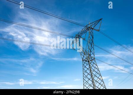 Photography of a High voltage tower, power line with electric cables and insulators against a blue sky with clouds and copy space. Stock Photo