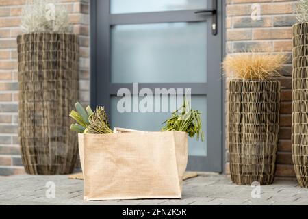 Shopping bag with fresh products from grocery on the doorstep at the front door of house. Contactless delivery concept. Stock Photo