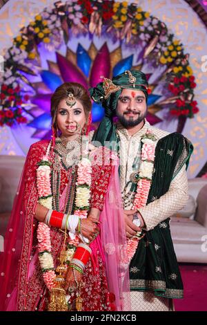 gorgeous stunning indian bride and groom wearing traditionally dress are posing on their wedding ceremony. Stock Photo