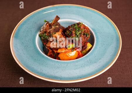 Stewed beef with potatoes and vegetables in a blue plate. Stock Photo