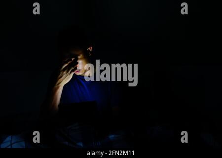 man using tablet to reading in bed and turning off the lights before getting some shut-eye sleep. working on bed Stock Photo