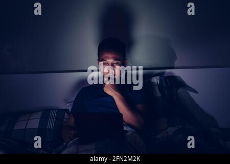 man using tablet to reading in bed and turning off the lights before getting some shut-eye sleep. working on bed Stock Photo