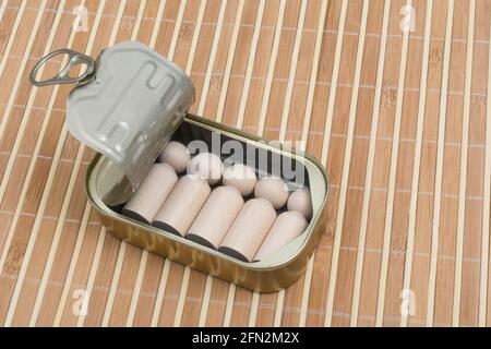Tinned fish can with small wood figures representing humans. For packed in like sardines, no room to move, tight fit, squashed together, overcrowded. Stock Photo