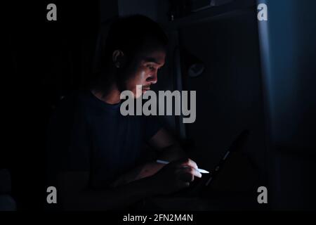 man using tablet to reading in bed and turning off the lights before getting some shut-eye sleep. working on bed Stock Photo