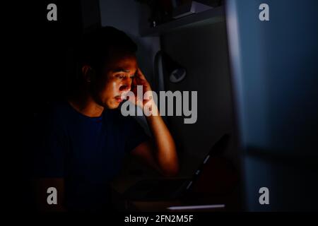 man using tablet to reading in bed and turning off the lights before getting some shut-eye sleep. working on bed Stock Photo