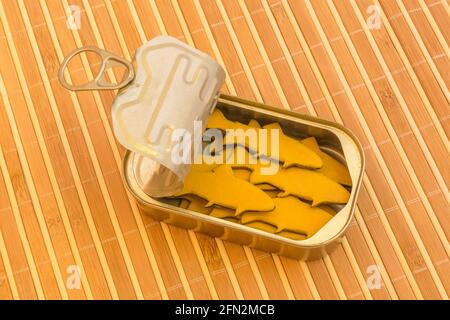 Tinned fish can with small wood figures of fish. For packed in like sardines, no room to move, tight fit, squashed together, overcrowded abstract. Stock Photo