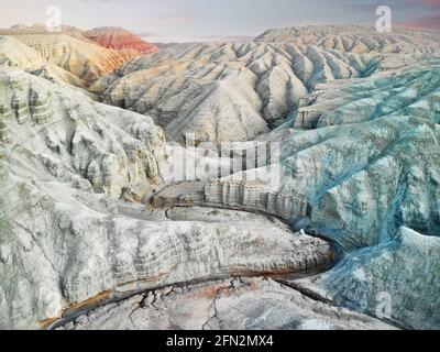 Aerial drone Landscape of Bizarre layered red, blue and white desert mountains with canyon in beautiful national park Altyn Emel in Kazakahstan Stock Photo