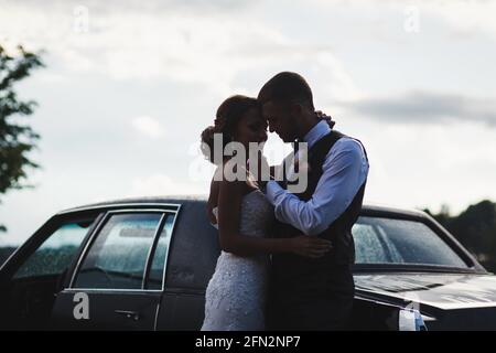 Silhouette of bride and groom near car on sunset background. wedding travel concept Stock Photo