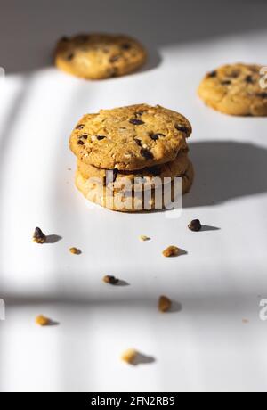 Chocolate chip cookies and crumbs on white background under the sunshine in front of the window Stock Photo