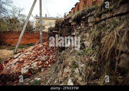 a brick wall destroyed by an explosion. the war destroys historical buildings. there was a house collapse. the ruins of the old fortress lie on the gr Stock Photo