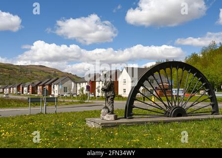 Merthyr Vale, Wales - May 2021: Old pit wheel on a roundabout at the entrance to a new housing development near Merthyr Tydfil. The houses are built o Stock Photo